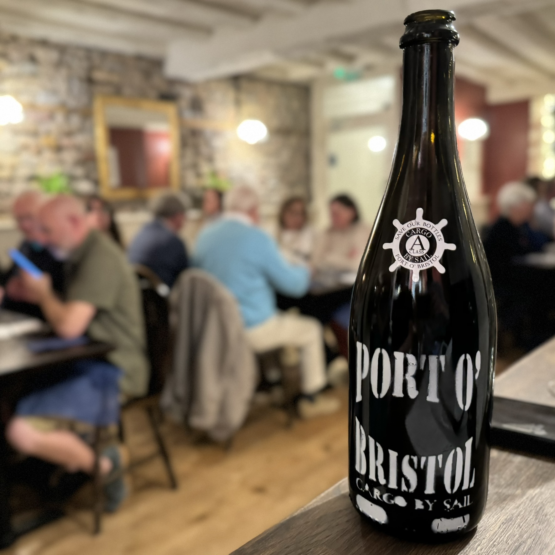 Port O' Bristol wine bottle with tasting event in background.